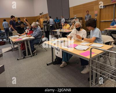 Germantown, Maryland, USA. 26.. Juli 2022. Teams von überparteilichen Abwesenden öffnen und überprüfen die Wahlzettel, bevor sie während der Wahlbeobachter tabelliert werden. Wenn es eine Frage zu einer Abstimmung gibt, hebt das Teammitglied seine Hand, um Hilfe zu erhalten. (Bild: © Sue Dorfman/ZUMA Press Wire) Stockfoto