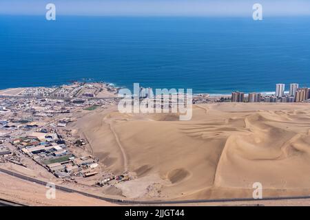 Die riesigen Sanddünen von Cerro Dragon mit der Stadt Iquique, Chile hinter der Küste des Pazifischen Ozeans. Stockfoto