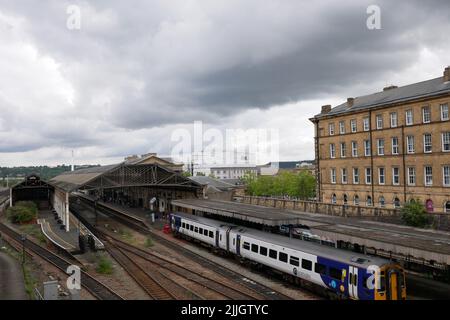 Silber und blau zwei Wagen nördlichen Eisenbahn-Zug in Station geparkt anderen Linien und Gebäuden wolkigen Himmel Stockfoto