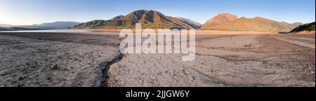 Panorama schöne Landschaft mit untergehenden Sonne: Berge, See und zerrissene Erde - ausgetrockneter flussbogen. Speicherplatz kopieren. Stockfoto