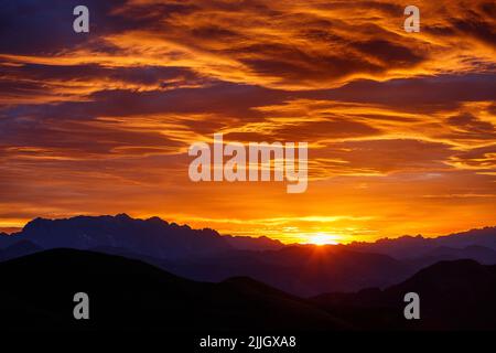 Erstaunliche Sonnenfarben im Morgengrauen. Rötlich bunte Wolken. Himmel in Flammen. Hochkönig und Dachstein Bergprofile. Österreichische alpen. Europa. Stockfoto