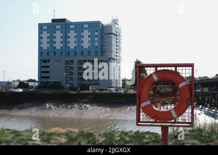 Blick über den Fluss Hull bei Ebbe mit Blick über das Premier Inn Hotel mit einem Rettungsring, der an einem Pfosten am Flussufer angebracht ist. Stockfoto