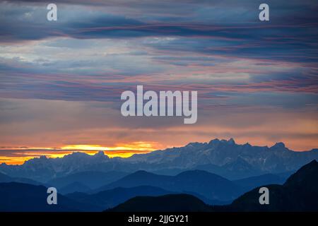 Bergprofile im Morgengrauen. Wolken durch Sonnenlicht gefärbt. Blick auf die Gipfel des Hohen Dachsteins. Österreichische Alpen. Europa. Stockfoto