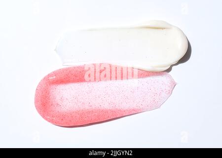 Creme- und Peeling-Flecken verschmieren Striche isoliert auf weißem Hintergrund. Kosmetische Peeling-Peeling-Textur. Rosa und weiße Hautpflegeproben. Stockfoto