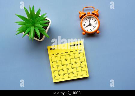 November 2023 Kalender auf Haftnotiz mit Wecker auf 8 Uhr eingestellt. Stockfoto