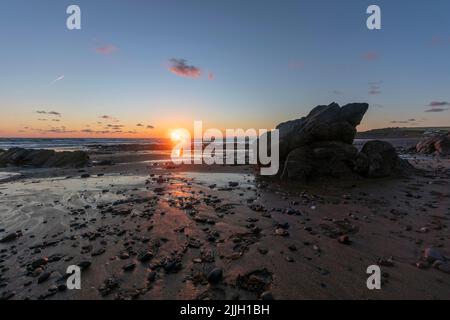 Widemouth Bay in der Nähe von Bude in Cornwall. Sonnenuntergang, die Gezeiten verlassen einen feuchten Sandstrand. Ein weiterer Kontinent (Nordamerika) ist nur wenige Stunden entfernt. Stockfoto