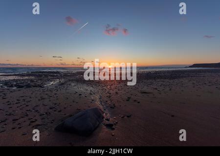 Widemouth Bay in der Nähe von Bude in Cornwall. Sonnenuntergang, die Gezeiten verlassen einen feuchten Sandstrand. Ein weiterer Kontinent (Nordamerika) ist nur wenige Stunden entfernt. Stockfoto