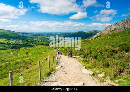 SNOWDON, WALES - 09. JULI 2022: Wanderer gehen vom Mount Snowdon aus nach dem Erreichen des Gipfels in der Morgendämmerung Stockfoto