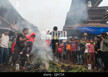 Bhaktapur, Nepal. 26.. Juli 2022. Ein Junge springt während der Feierlichkeiten über das Feuer. Das Ghantakarna-Fest ist eine Feier der Niederlage des mythischen Dämons Ghantakarna, der den bösen Geistern hinterherjagt und Gutes bringt. Kredit: SOPA Images Limited/Alamy Live Nachrichten Stockfoto