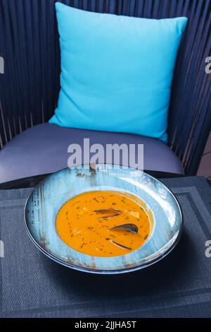 Köstliche Meeresfrüchte Tomatensoße mit Bouillabaisse Fischsuppe mit Garnelen, Muscheln und Fisch auf einem blauen Teller auf dem Tisch. Köstliches romantisches Abendessen in einer Fischruhe Stockfoto