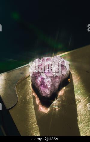 Funkelnder purpurner Amethyst-Kristallgeodenteller auf einem Messinggoldtisch Stockfoto
