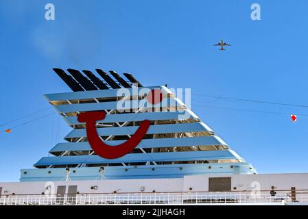 Korfu, Griechenland - Juni 2022: TUI-Logo auf dem Trichter eines von Marella Cruises betriebenen Kreuzfahrtschiffs mit einem Urlaubsjet über dem Schiff Stockfoto