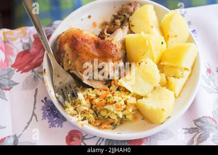 Gebratenes Hähnchenschenkel mit Kartoffeln und Salat Stockfoto