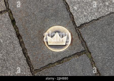 Bratislava, Slowakei - 19. April 2012: Kronenförmige Fliese auf dem Boden als Symbol des Krönungsweges. Messingkronenmarkierung in der Kopfsteinpflasterstraße Stockfoto