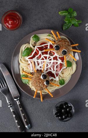 Koteletts sehen aus wie Spinnen mit Oliven und Trinkhalmen, serviert mit Spaghetti-Nudeln und Tomatensauce. Halloween Frühstücksidee, Draufsicht Stockfoto