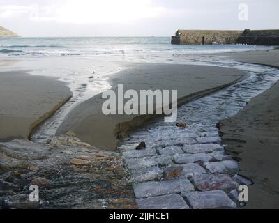 Kobbles unter dem Sand, wo der Strom auf das Meer im Gorran Haven Hafen trifft Stockfoto