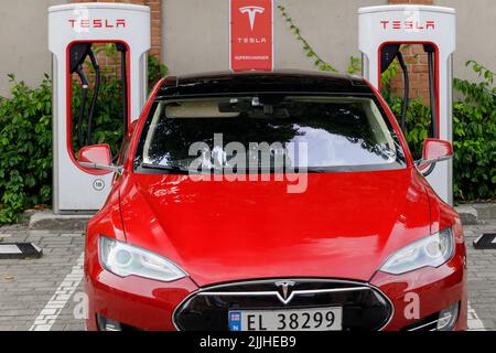 Posen, Polen. 26 Jul 2022: Rote Tesla Motors Elektroautos parkten an Ladegeräten einer Tesla-Ladestation in der Stadt Poznan, Polen. Frontansicht. Stockfoto