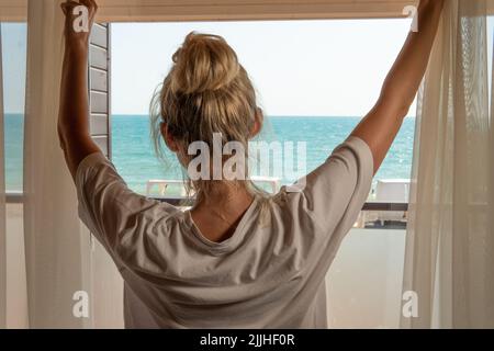 Meer Vorhänge Fenster Frau zu Hause offen Morgen zurück öffnende Person, von hellen Wohnung in gesund für junge Hoffnung, entspannen Schönheit. Dame allein, Stockfoto