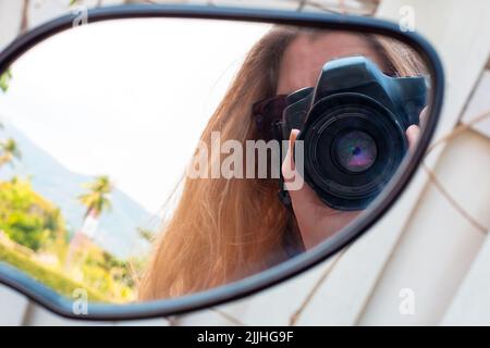 Lgirl mit langen blonden Haaren nimmt ein Foto auf, das sich im Rückspiegel widerspiegelt Stockfoto