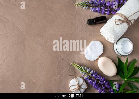 Natürliche Bio-Kosmetik und Lupine Blumen auf Bastelpapier Hintergrund. Feuchtigkeitsspendende Creme, Seife und Handtuch. Körperpflegekonzept. Spa und Schönheitsbehandlungen Stockfoto