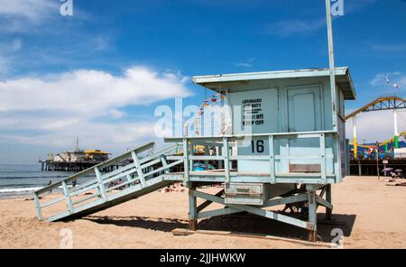 Ein hellblauer Rettungsschwimmer steht am Strand in Santa Monica Kalifornien mit dem Pier und seinen Fahrgeschäften im Hintergrund. Stockfoto