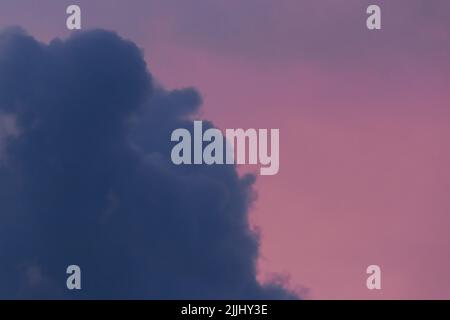 Dunkelblaue Wolke gegen den rosa Abendhimmel nach dem Regen Natur Farbe Hintergrund. Stockfoto