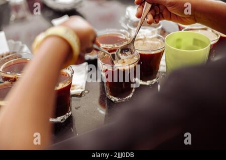 Tasse Schnuppermann mit Löffeln in den Händen Verkostung Kaffee Stockfoto