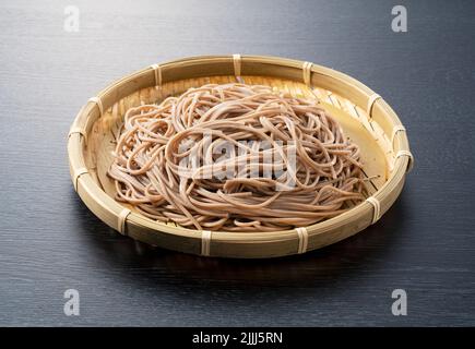 Zaru soba vor schwarzem Hintergrund platziert. Zaru Soba ist ein traditionelles japanisches Essen. Stockfoto