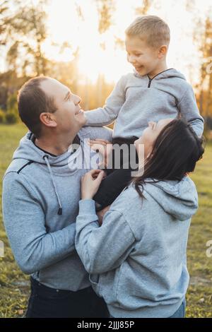 Fröhlicher Vater und Mutter, die mit ihren Kindern im Park spielen. Liebe Zeit. Gesunder Lebensstil. Frohe, liebevolle Familie. Stockfoto
