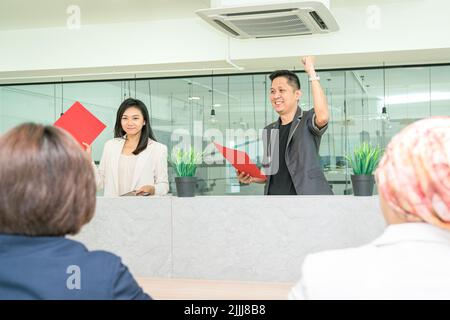 Der Geschäftsmann hebt die Hand und feiert während eines Treffens mit dem Personal mit der Faust. Geschäftserfolg oder Siegeskonzept. Stockfoto