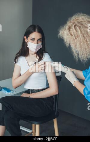 Arzt hält Spritze und mit Baumwolle vor der Injektion an den Patienten im Krankenhaus. Frau mit Gesichtsmaske geimpft, Coronavirus, covid-19 Stockfoto