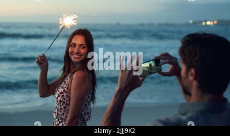 Schöne Frau hält Sparkler posiert für Foto am romantischen Strand feiern Silvester bei Sonnenuntergang Stockfoto