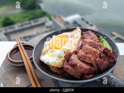 Reis mit rotem Grillfleisch, Spiegelei und gedünstetem pak-Choi-Kohl mit roter Sauce und Holzstäbchen auf Holzschneidebrett servieren. Asiatischer Essensstil Stockfoto