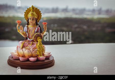 Hinduistischer Kosmos Maha laxshmi Statue mit Blumengirlande mit Naturhintergrund verziert. Statue der Göttin des Reichtums, Raum für Text, selektiver Fokus. Stockfoto