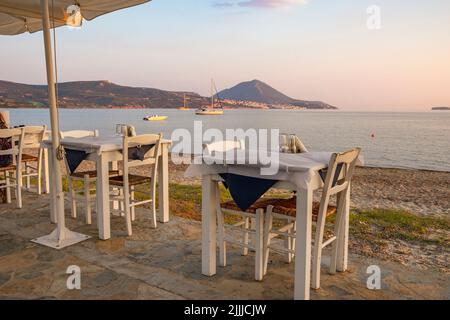 Typisch griechischer Tavernentisch am Meer mit Holzstühlen an der Küste von Gialova in der Nähe von Pylos, Messinia, Griechenland, Europa Stockfoto
