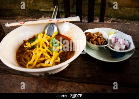 Lokale traditionelle thailändische Küche khao soi gai oder Küche nördliche thai-Kurrsuppe Nudeln mit Huhn servieren Gemüse Beilage auf Keramik Teller auf l Stockfoto