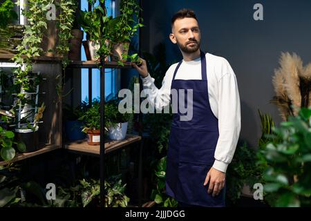 Floristin neben einem Regal mit Topfpflanzen Stockfoto