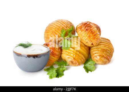 Leckere gebackene Kartoffeln und eine Schüssel mit Sauerrahm auf weißem Hintergrund Stockfoto