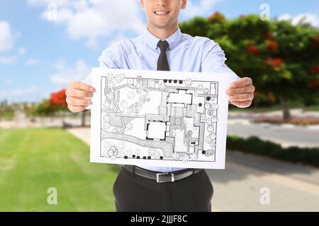 Junger männlicher Landschaftsdesigner mit neuem Projekt im Freien Stockfoto