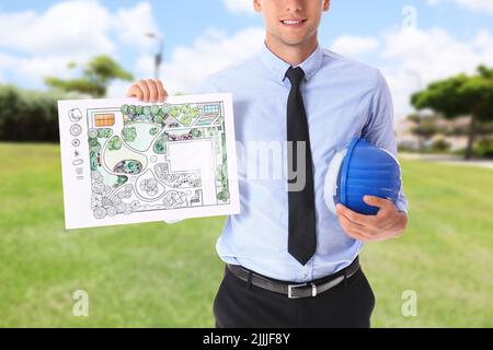 Junger männlicher Landschaftsdesigner mit neuem Projekt und Hardhut im Freien Stockfoto