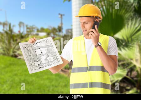 Junger männlicher Landschaftsdesigner mit neuem Projekt, der mit dem Mobiltelefon im Freien spricht Stockfoto