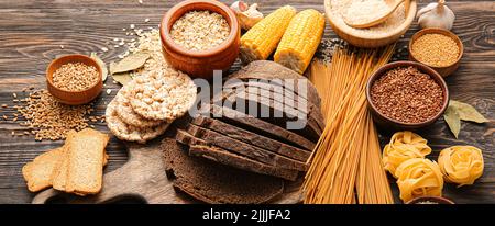 Frisches Brot in Scheiben mit verschiedenen Produkten auf Holzhintergrund Stockfoto