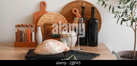 Frisches Brot mit Rotwein und Küchenutensilien auf dem Tisch Stockfoto