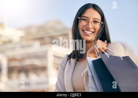 Ermäßigte Artikel sind Geschenke für alle Frauen. Porträt einer attraktiven jungen Frau, die beim Einkaufen in der Stadt allein nach draußen geht. Stockfoto