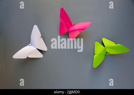 Grün, rosa und weiß Papier Schmetterling Origami isoliert auf einem weißen grauen Hintergrund. Stockfoto