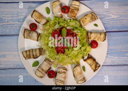 REZEPT FÜR GEGRILLTE AUBERGINENROLLE GEFÜLLT MIT RICOTTA-KÄSE UND SALAT MIT VINAIGRETTE Stockfoto