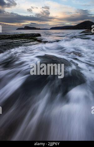 Wasser rauscht über Felsen am Umina Point an der zentralen Küste von NSW Stockfoto
