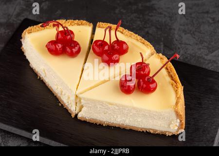 Klassischer Käsekuchen mit Kirschen auf dunklem Hintergrund. Stockfoto