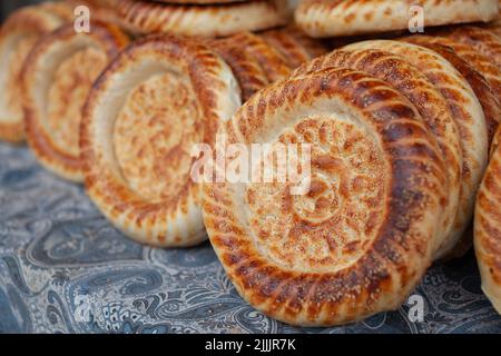 Typisches traditionelles Fladenbrot mit knuspriger Kruste mit Sesam, der gerade in Tandoor gebacken wurde, auf dem Markt einer alten Bäckerei. Frisches Brot mit leckeren Aromen von cla Stockfoto