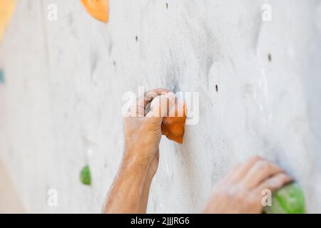 Nahaufnahme einer männlichen Hand, die mit Magnesiumpulver verschmiert wurde und an einer Kletterwand griff. Stockfoto